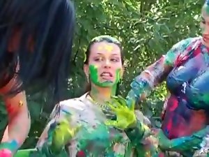 Girls spread body paint on each other outdoors
