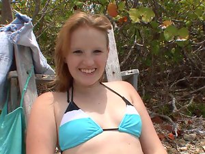 A smiling blue eyed honey is playing with a pecker on the beach