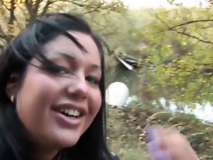 Dark-haired babe is in nature with her partner and he wants his cock licked